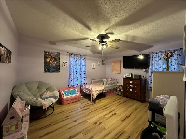 bedroom with light wood-type flooring, ceiling fan, and a textured ceiling