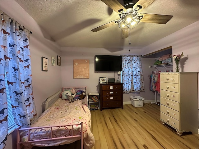 bedroom featuring a textured ceiling, light wood-type flooring, and a ceiling fan