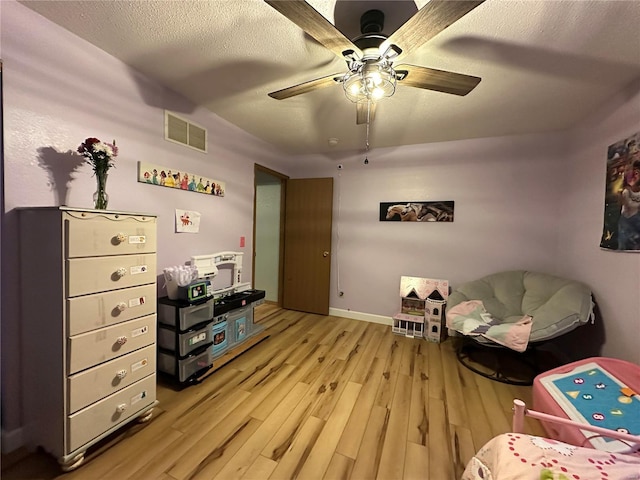 sitting room with visible vents, baseboards, a ceiling fan, a textured ceiling, and light wood-style floors