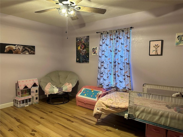 bedroom featuring a textured ceiling, light wood-type flooring, a ceiling fan, and baseboards