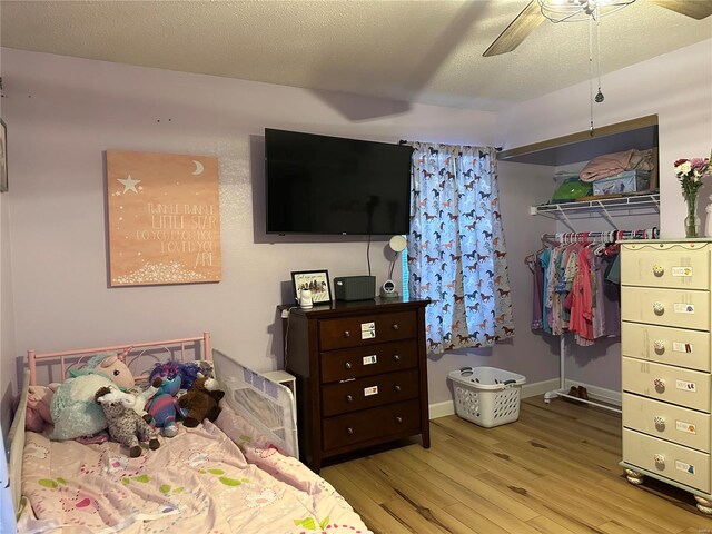 bedroom featuring a closet, ceiling fan, a textured ceiling, wood finished floors, and baseboards