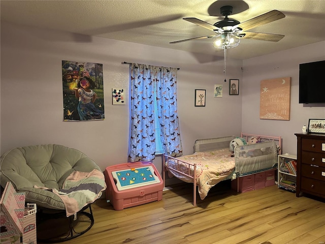 bedroom featuring a textured ceiling, a ceiling fan, and wood finished floors