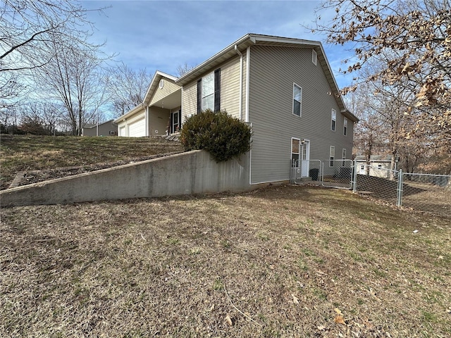 view of property exterior featuring an attached garage, fence, and a gate