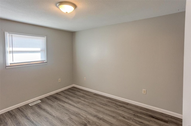 spare room with dark hardwood / wood-style floors and a textured ceiling