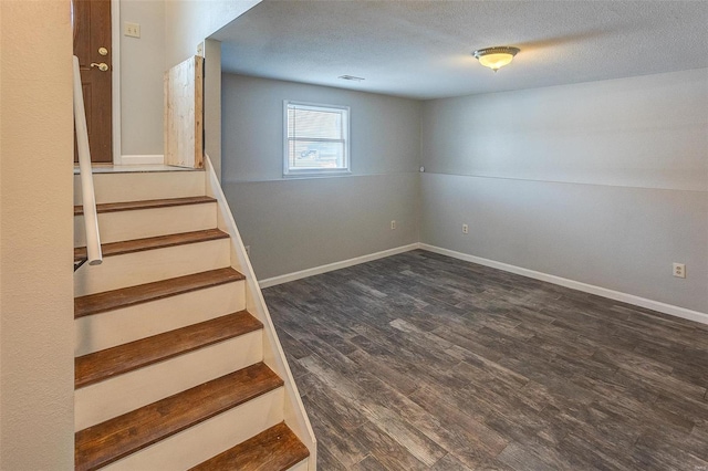 basement with dark wood-type flooring and a textured ceiling