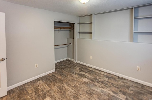 unfurnished bedroom with dark wood-type flooring, a textured ceiling, and a closet