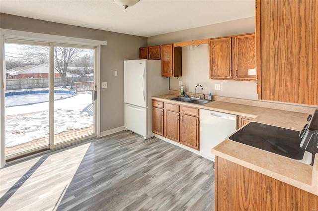 kitchen with sink, white appliances, a textured ceiling, and light wood-type flooring