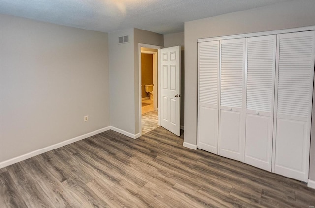 unfurnished bedroom with dark hardwood / wood-style flooring, a closet, and a textured ceiling