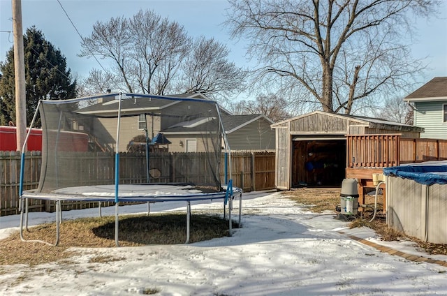 yard covered in snow with a covered pool, a trampoline, and a storage unit