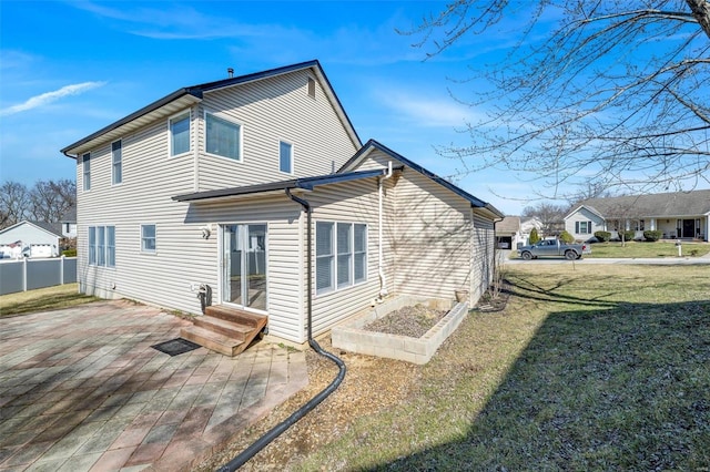 rear view of house with entry steps, a patio, a lawn, and fence