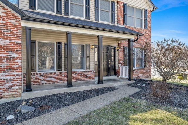 property entrance with a porch and brick siding