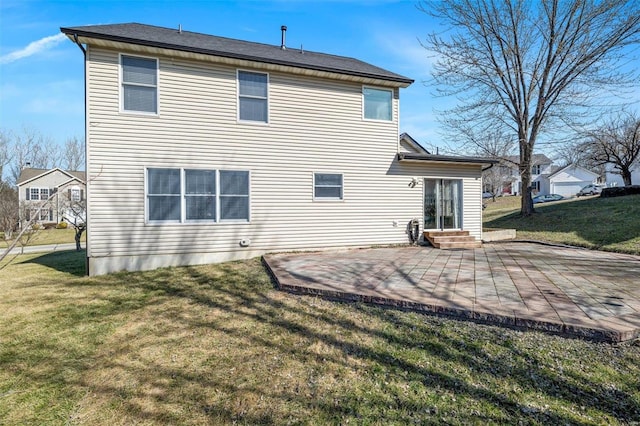 rear view of property featuring entry steps, a patio, and a lawn