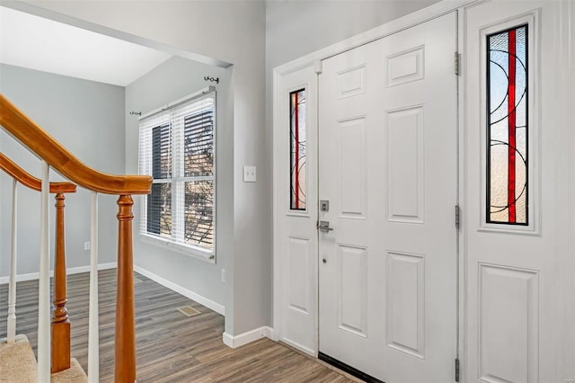 foyer with stairs, baseboards, and wood finished floors