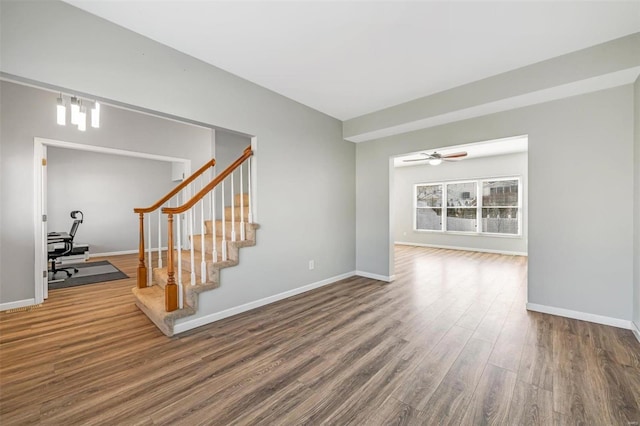 empty room with stairway, baseboards, and wood finished floors