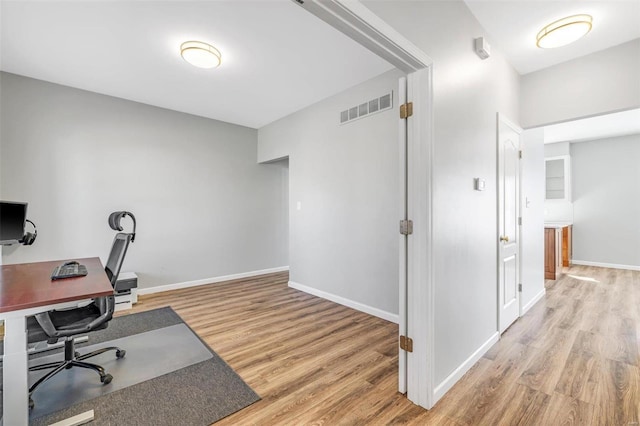 office space featuring baseboards, visible vents, and light wood-style floors