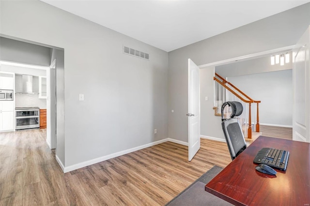 unfurnished office with light wood-type flooring, baseboards, and visible vents