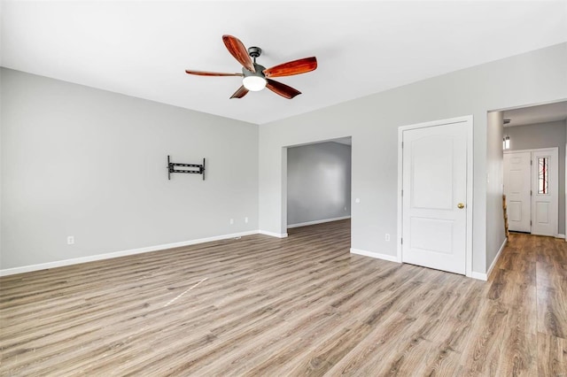 spare room featuring wood finished floors, a ceiling fan, and baseboards