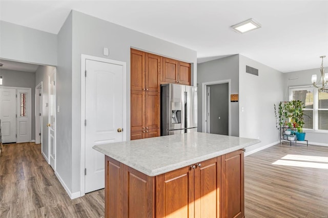 kitchen with a notable chandelier, brown cabinets, visible vents, and stainless steel fridge with ice dispenser