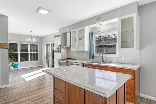 kitchen with brown cabinets, decorative backsplash, appliances with stainless steel finishes, light wood-style floors, and a sink