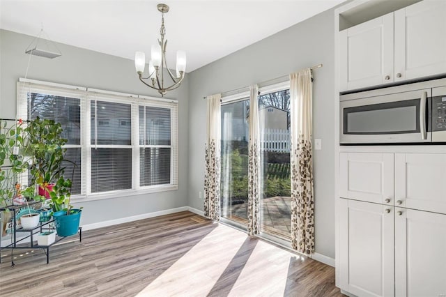 interior space with baseboards, a notable chandelier, and light wood finished floors