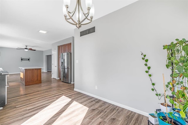 interior space with baseboards, visible vents, wood finished floors, and ceiling fan with notable chandelier