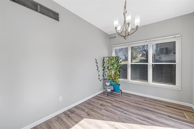 interior space featuring a notable chandelier, visible vents, baseboards, and wood finished floors