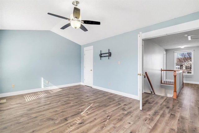 unfurnished room with a ceiling fan, vaulted ceiling, baseboards, and wood finished floors