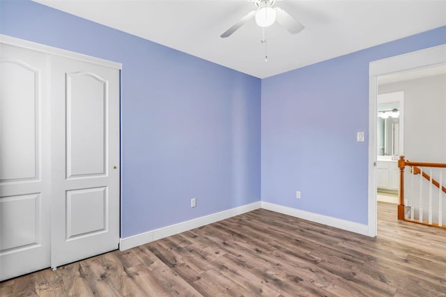 unfurnished bedroom featuring a closet, wood finished floors, and baseboards