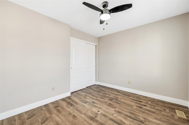 unfurnished bedroom with visible vents, baseboards, ceiling fan, wood finished floors, and a closet