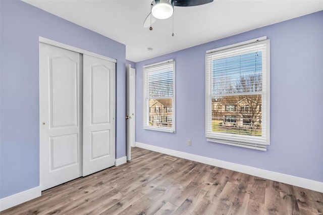 unfurnished bedroom with a ceiling fan, baseboards, a closet, and wood finished floors