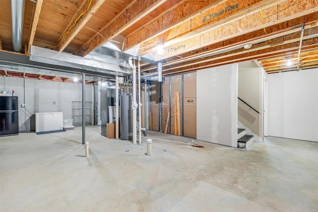 unfinished below grade area with freestanding refrigerator, water heater, and stairway