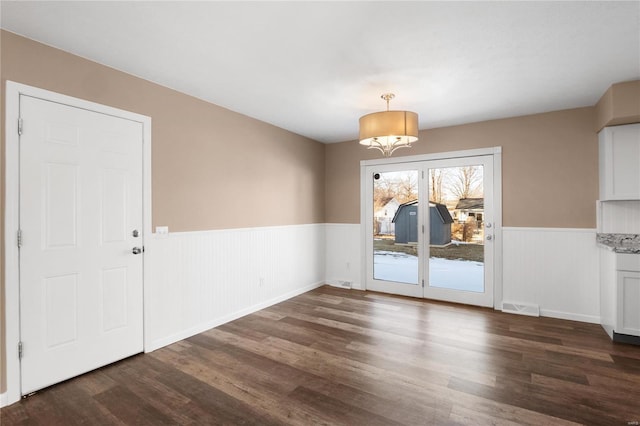 unfurnished dining area featuring dark wood-type flooring and an inviting chandelier