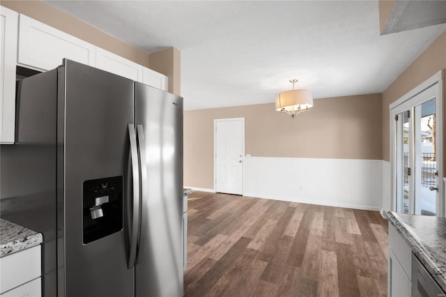 kitchen featuring wood-type flooring, stainless steel fridge with ice dispenser, hanging light fixtures, light stone countertops, and white cabinets