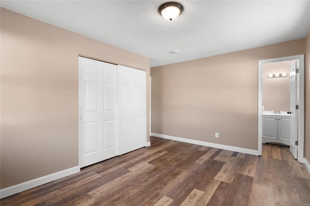 unfurnished bedroom featuring ensuite bath, dark hardwood / wood-style floors, sink, and a closet