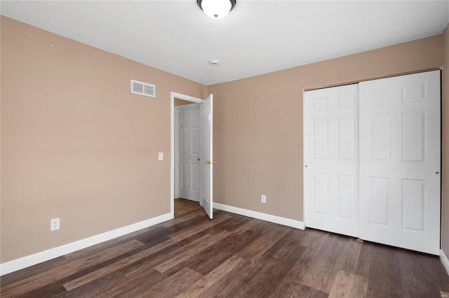 unfurnished bedroom with dark wood-type flooring and a closet