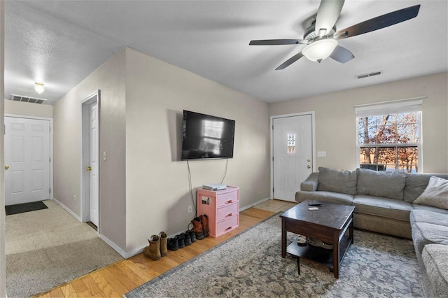 living room with ceiling fan, wood-type flooring, and a textured ceiling