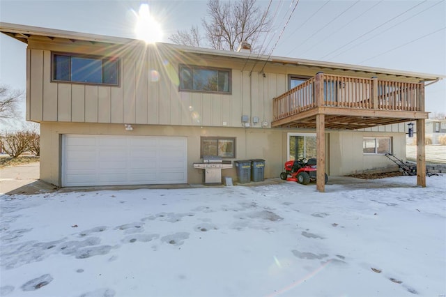 snow covered house featuring a garage and a deck