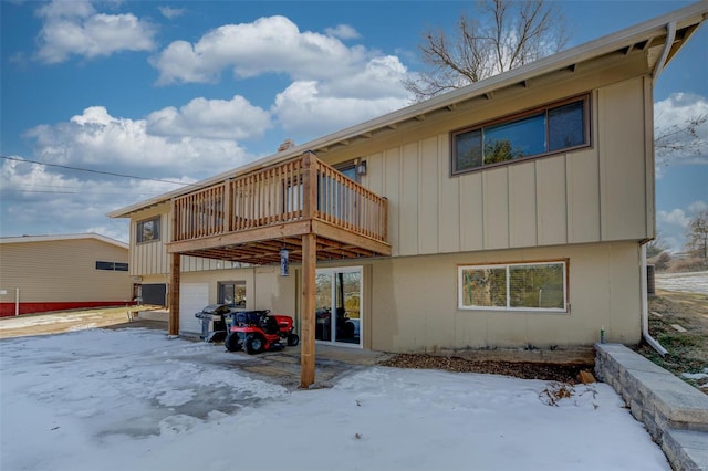 snow covered property featuring a wooden deck and a garage