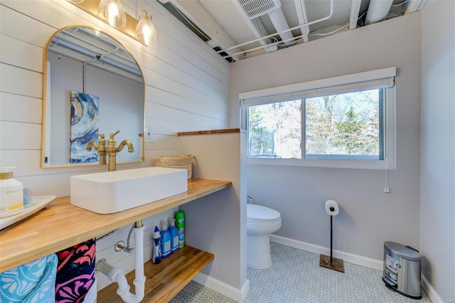 bathroom with tile patterned flooring, sink, wood walls, and toilet