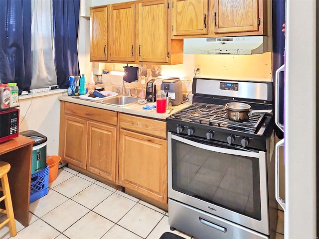 kitchen with light tile patterned floors, stainless steel gas range, fridge, and sink