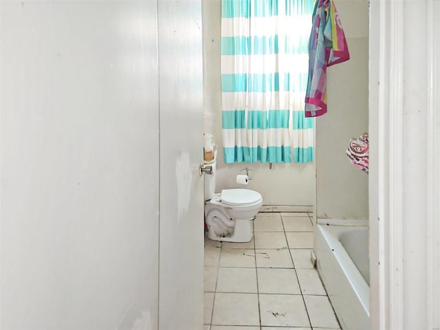 bathroom with tile patterned floors, a tub, and toilet