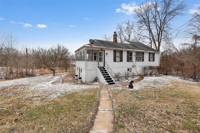 view of front of house with a sunroom and a front yard