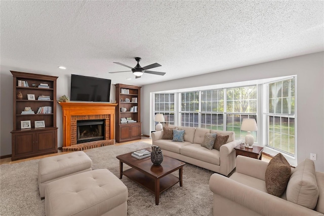 living room with ceiling fan, a fireplace, light carpet, and a textured ceiling