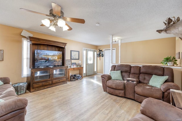 living room with a textured ceiling, ceiling fan, and wood finished floors