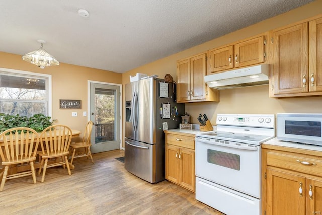 kitchen featuring white appliances, under cabinet range hood, light countertops, and light wood finished floors