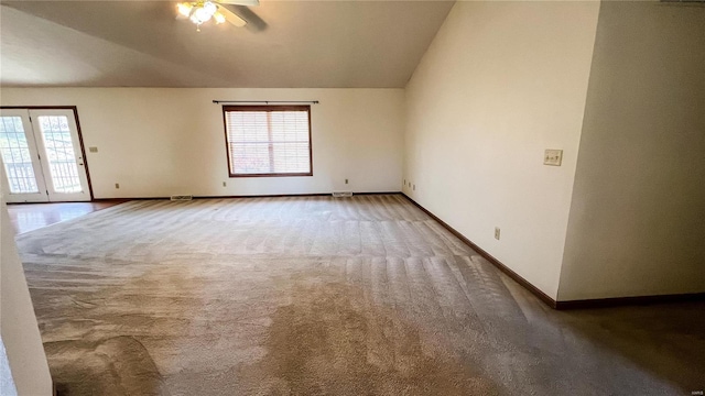 empty room featuring lofted ceiling, ceiling fan, a healthy amount of sunlight, and carpet