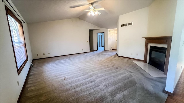 unfurnished living room featuring a tiled fireplace, lofted ceiling, light colored carpet, and ceiling fan