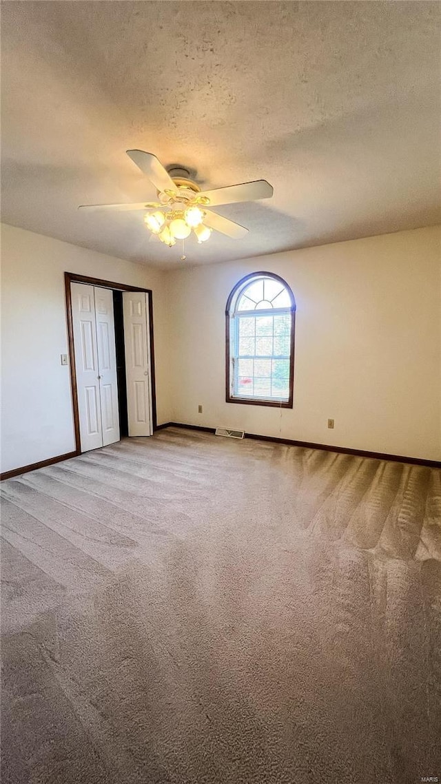 unfurnished bedroom featuring a textured ceiling, ceiling fan, and carpet flooring