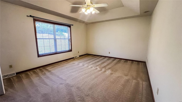 spare room featuring carpet floors, ceiling fan, and a tray ceiling