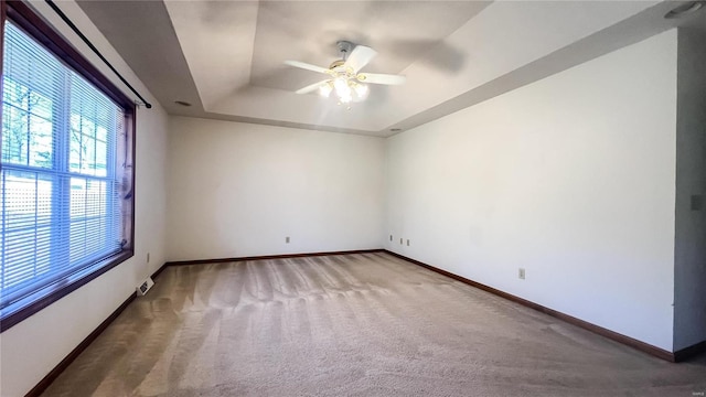 unfurnished room with a tray ceiling, ceiling fan, and carpet flooring